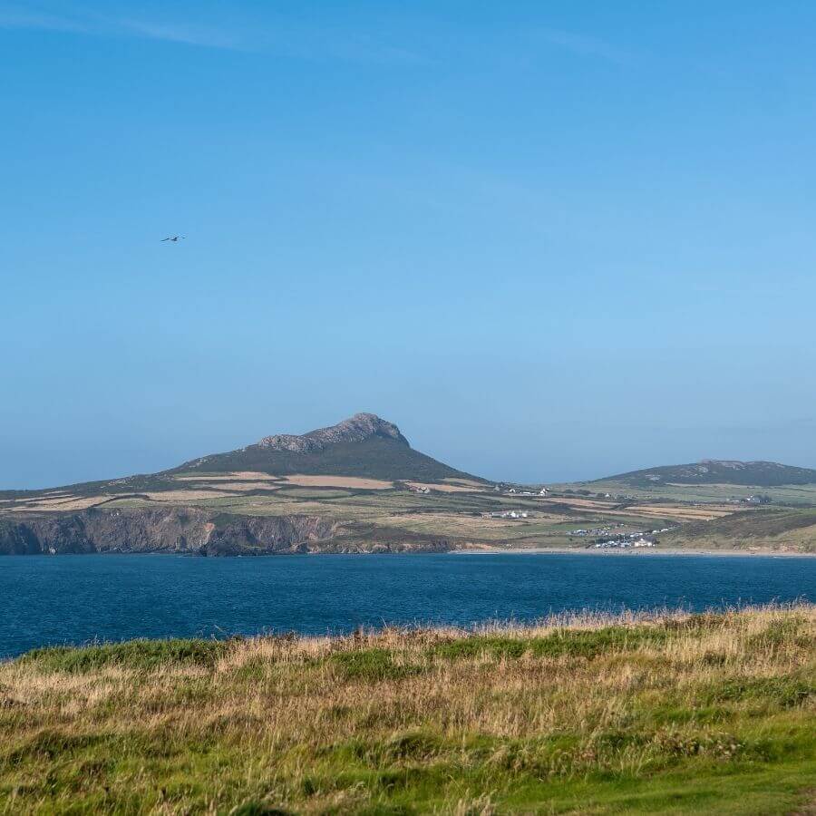View of Whitesands Bay near St Davids, with golden sands, rugged cliffs and the Pembrokeshire coastline stretching towards Ramsey Island.
